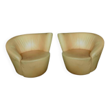 Pair of yellow leather swivel armchairs with asymmetrical armrests, circa 1980