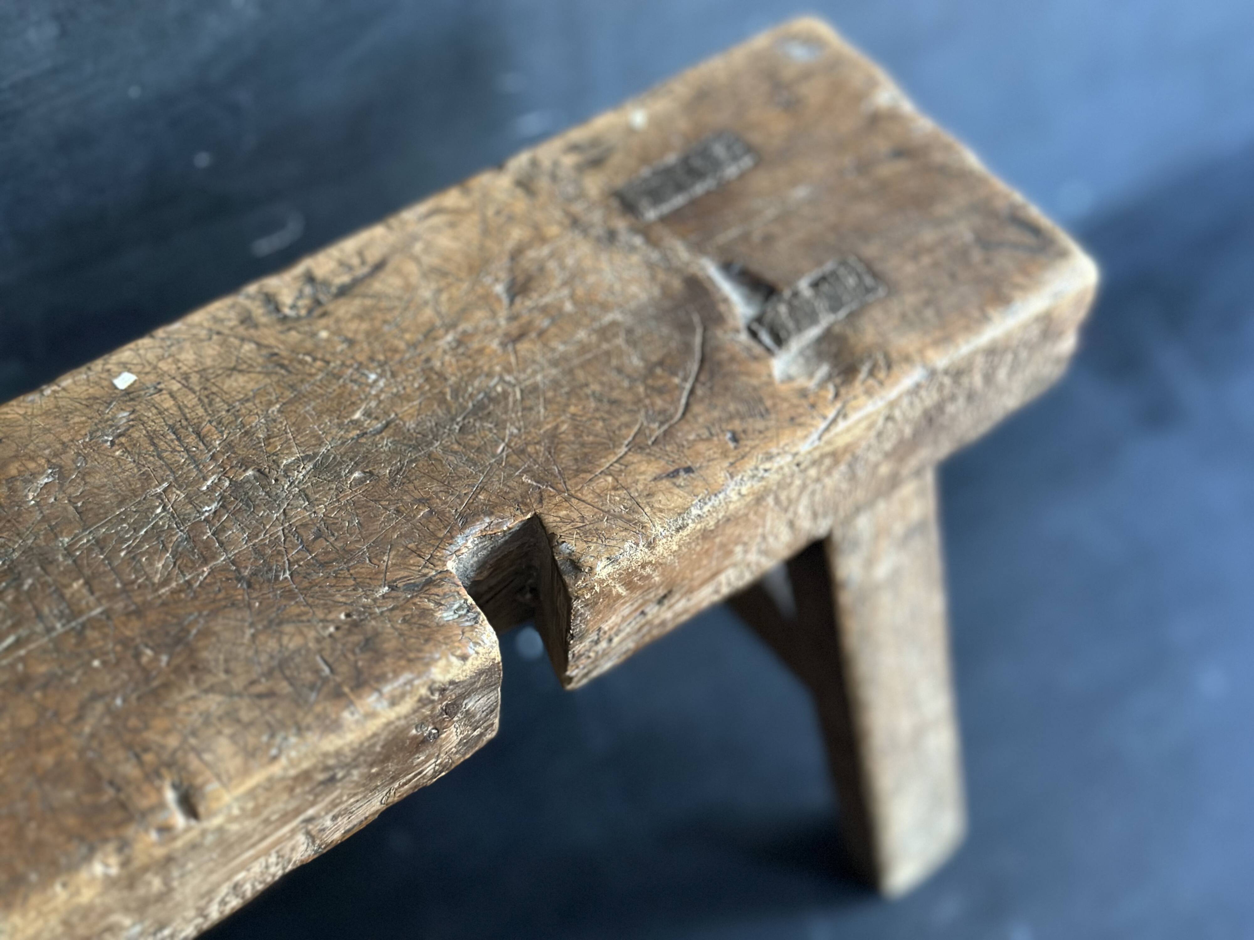 Ancient Chinese farm bench in patinated wood, small rustic stool.