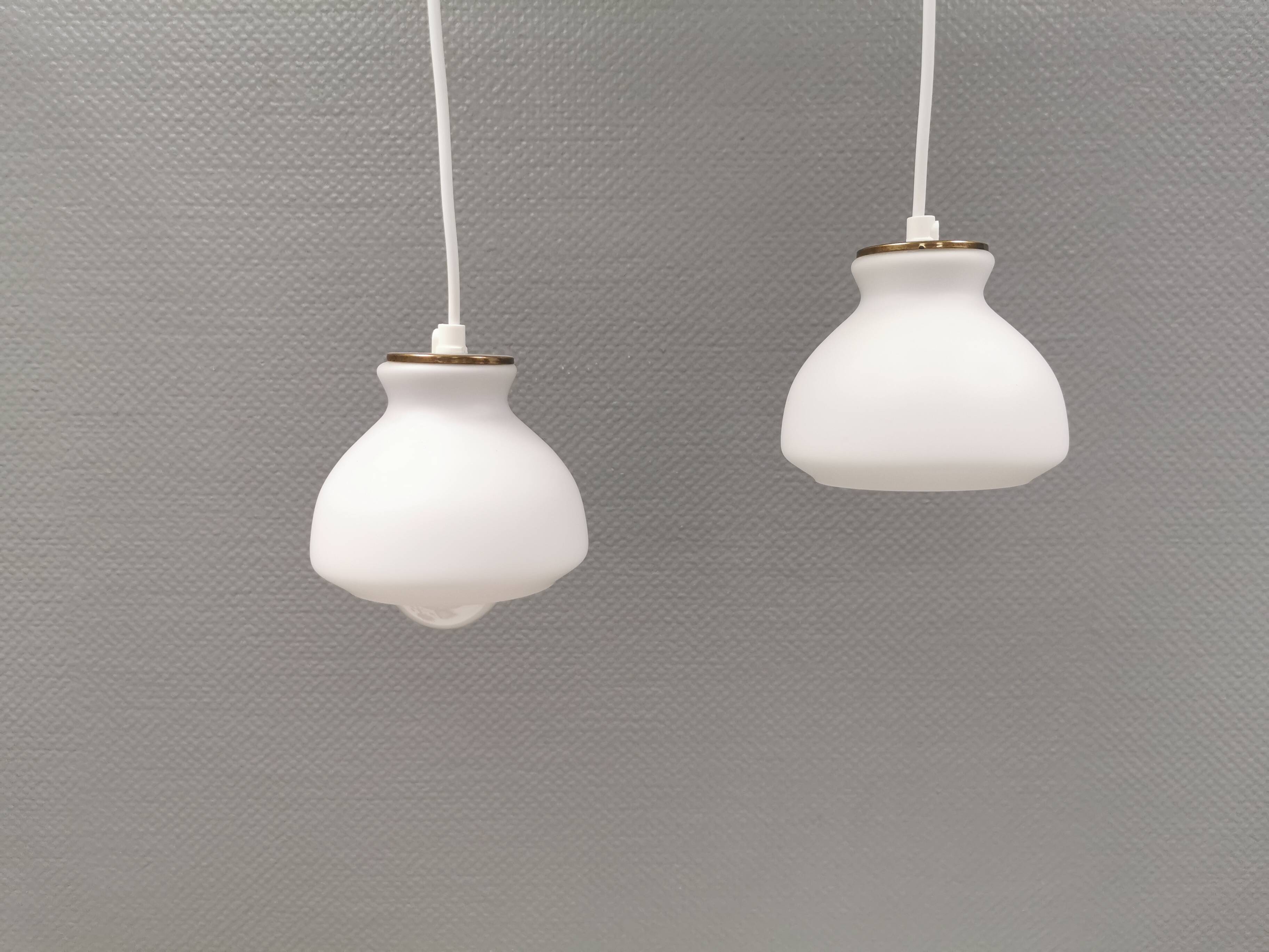 Une paire de lampes suspendues de la verrerie danoise Holmegaard avec abat-jour en verre blanc laiteux.