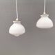 Une paire de lampes suspendues de la verrerie danoise Holmegaard avec abat-jour en verre blanc laiteux.