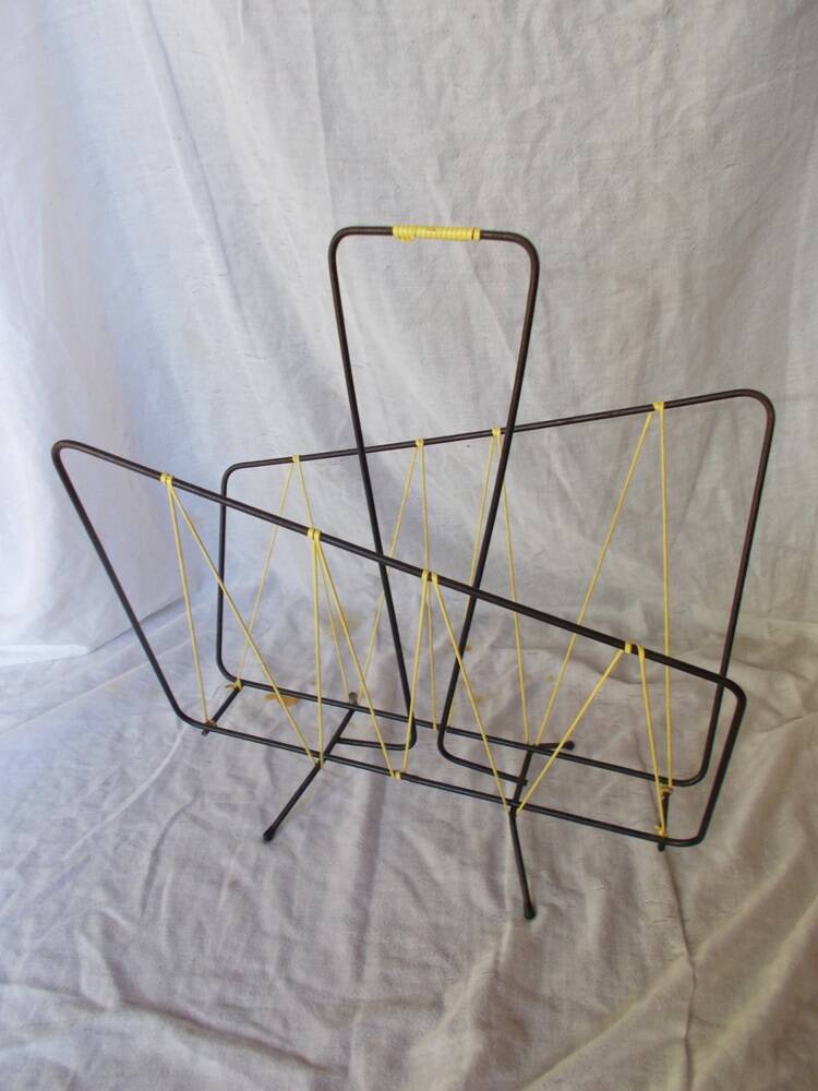 Black metal magazine rack with yellow scoubidou wire.