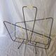 Black metal magazine rack with yellow scoubidou wire.
