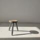 Small brutalistic tripod stool in dark wood tapered feet circular seat