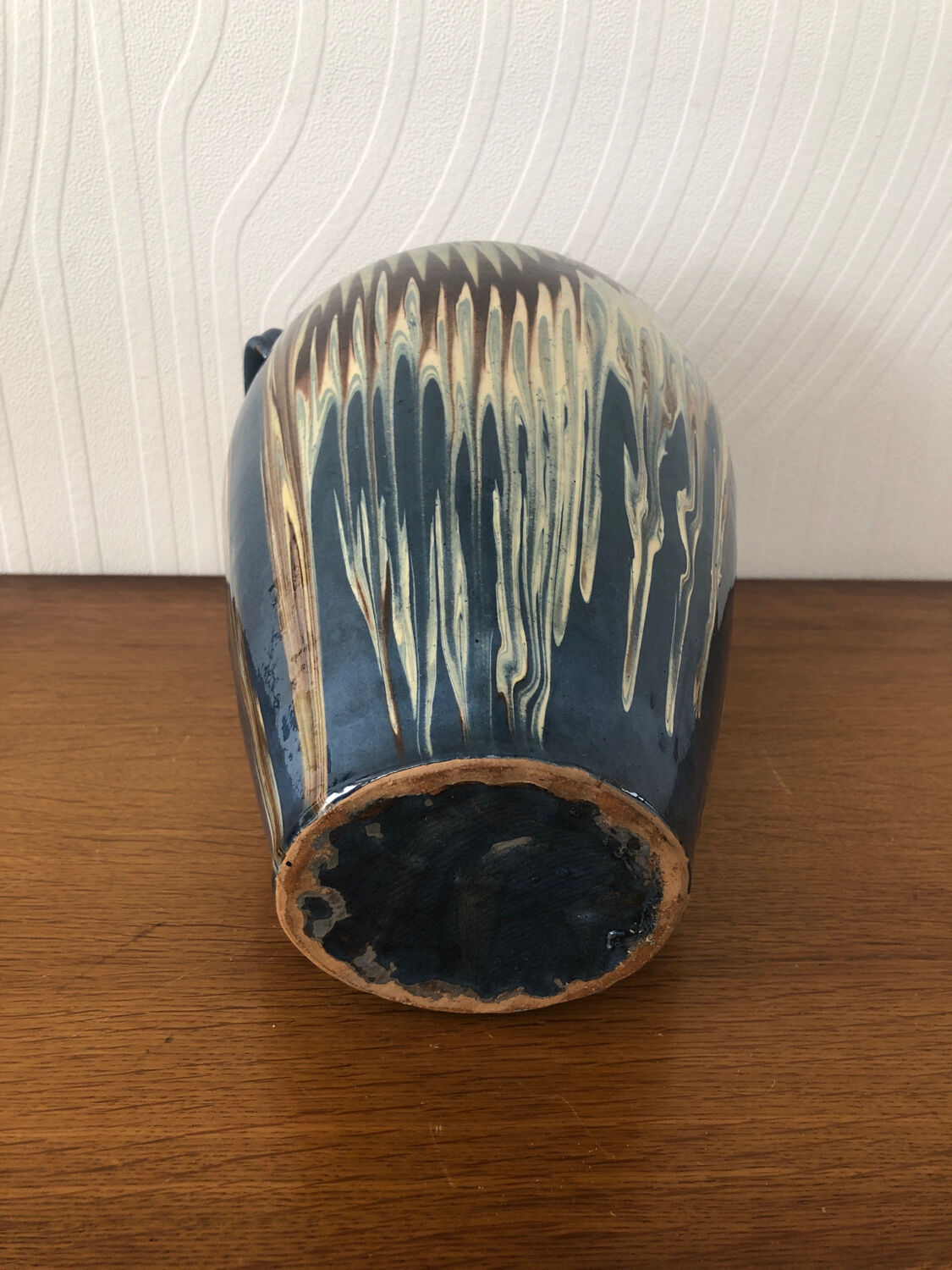 Vase in glazed ceramic decoration drips on blue background