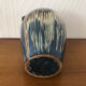 Vase in glazed ceramic decoration drips on blue background