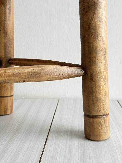 Antique tripod stool in light wood with a woven straw seat.