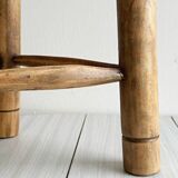 Antique tripod stool in light wood with a woven straw seat.