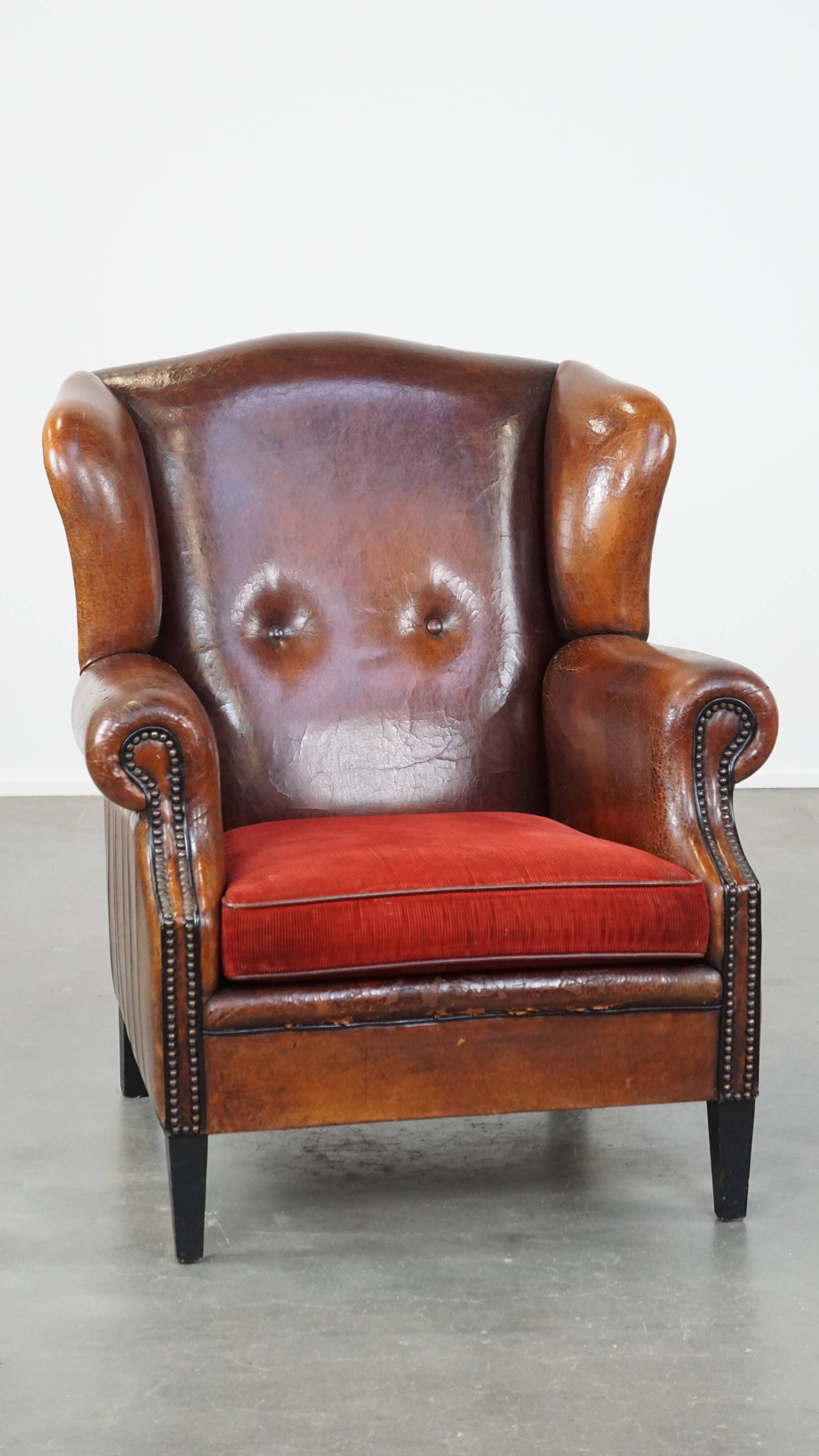 Sheepskin leather wingback chair with a red corduroy seat cushion