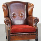 Sheepskin leather wingback chair with a red corduroy seat cushion