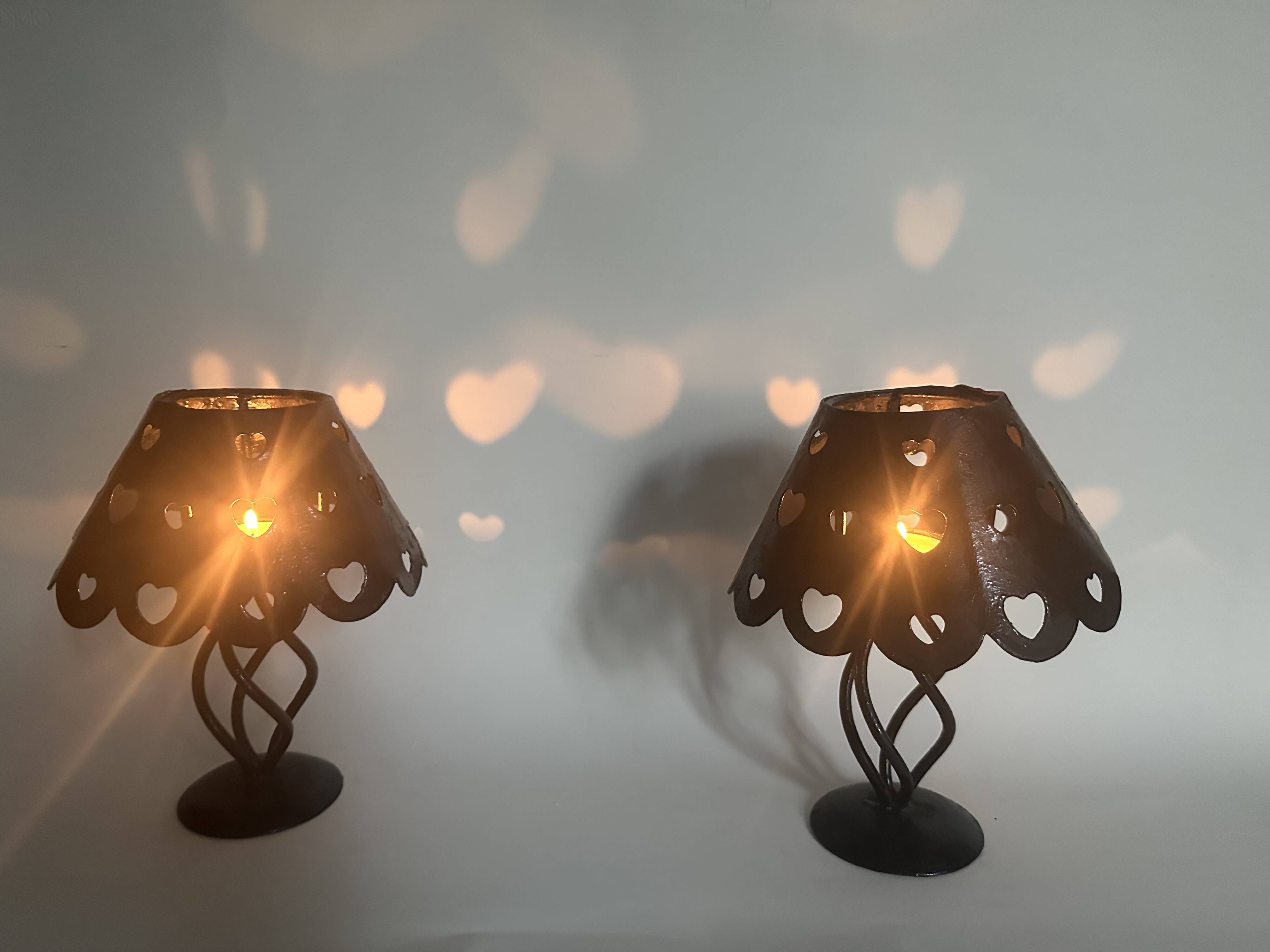 Pair of black wrought iron lanterns with heart patterns, romantic style.