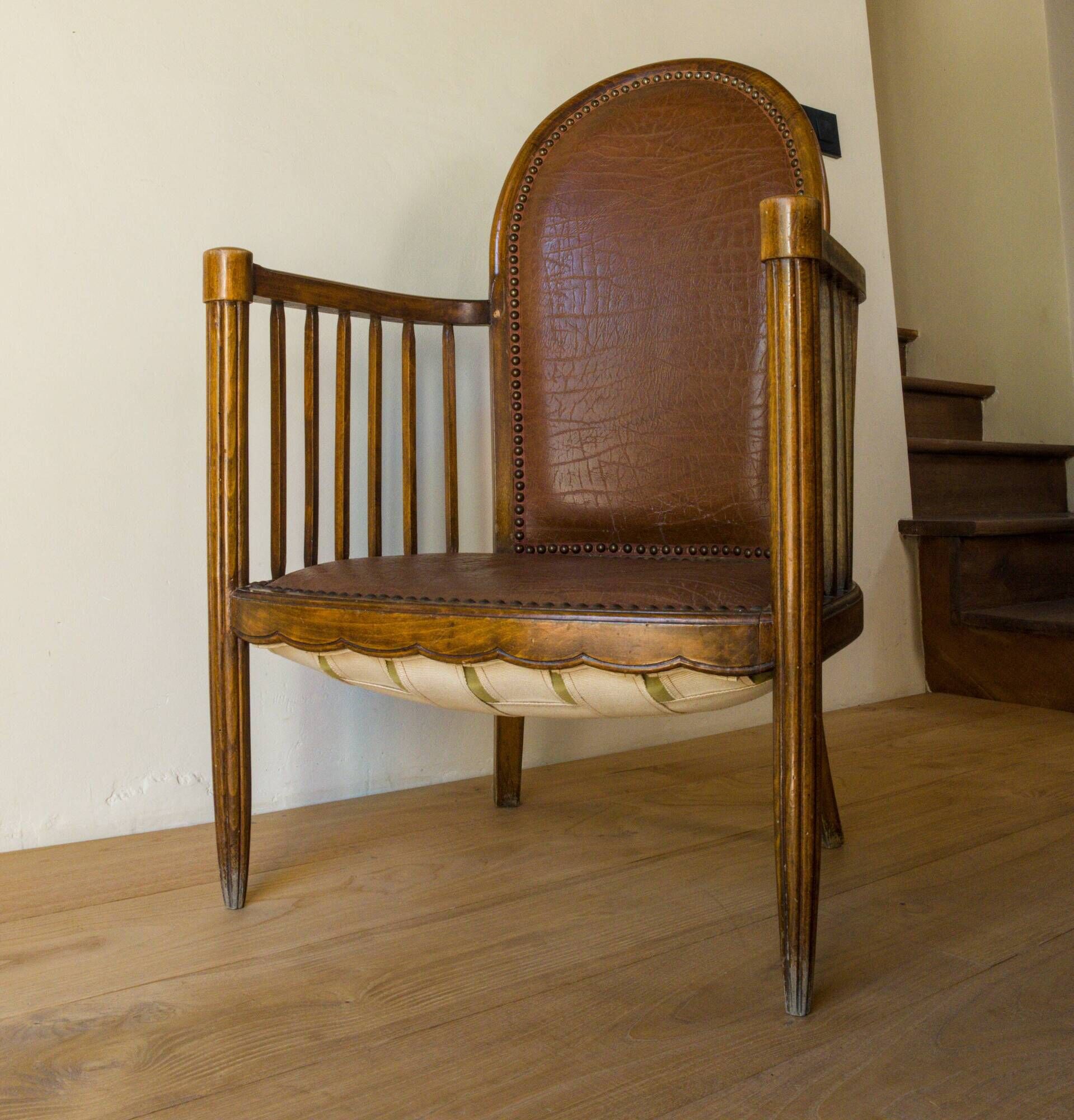 Antique armchair in solid wood and patinated brown leather, early 20th century.