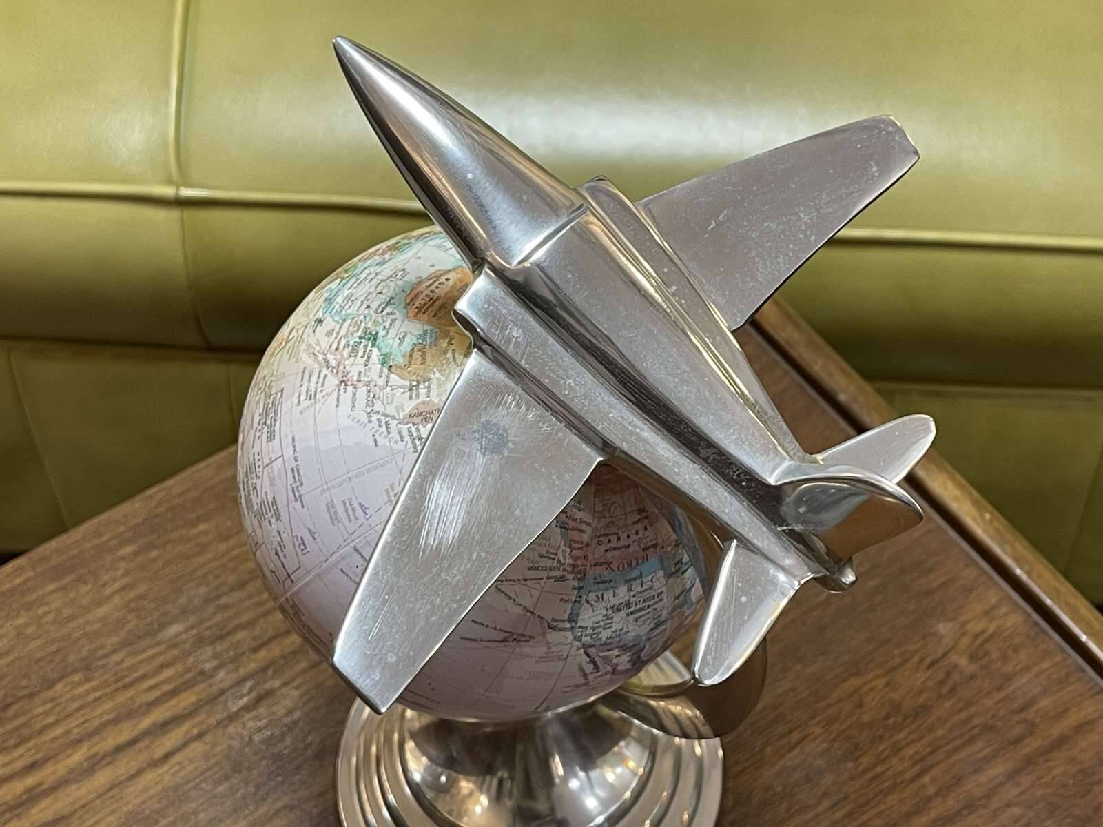 1960s terrestrial globe on a chrome stand with a plane flying over it.