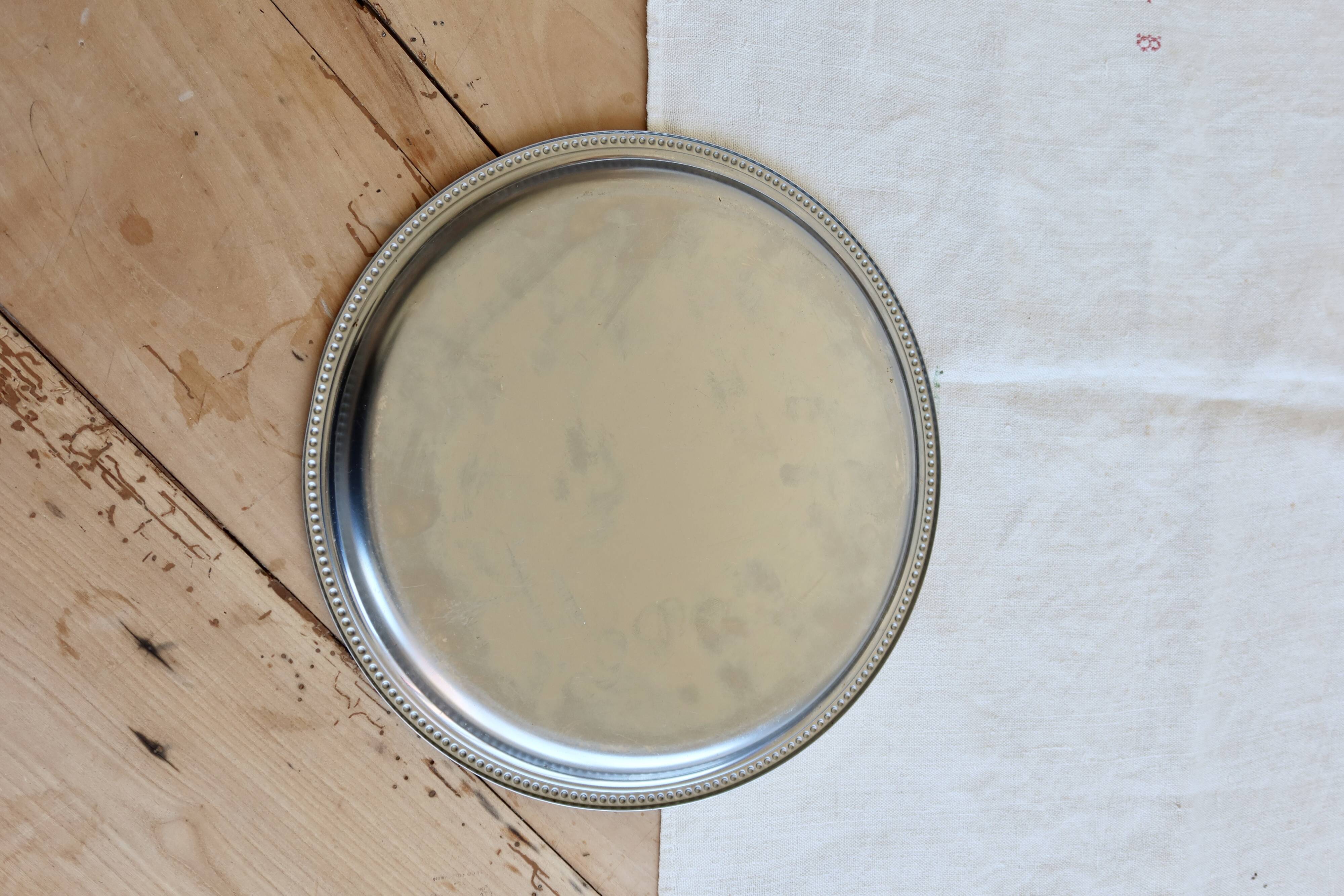 Vintage round metal plate with silver trim and beads.