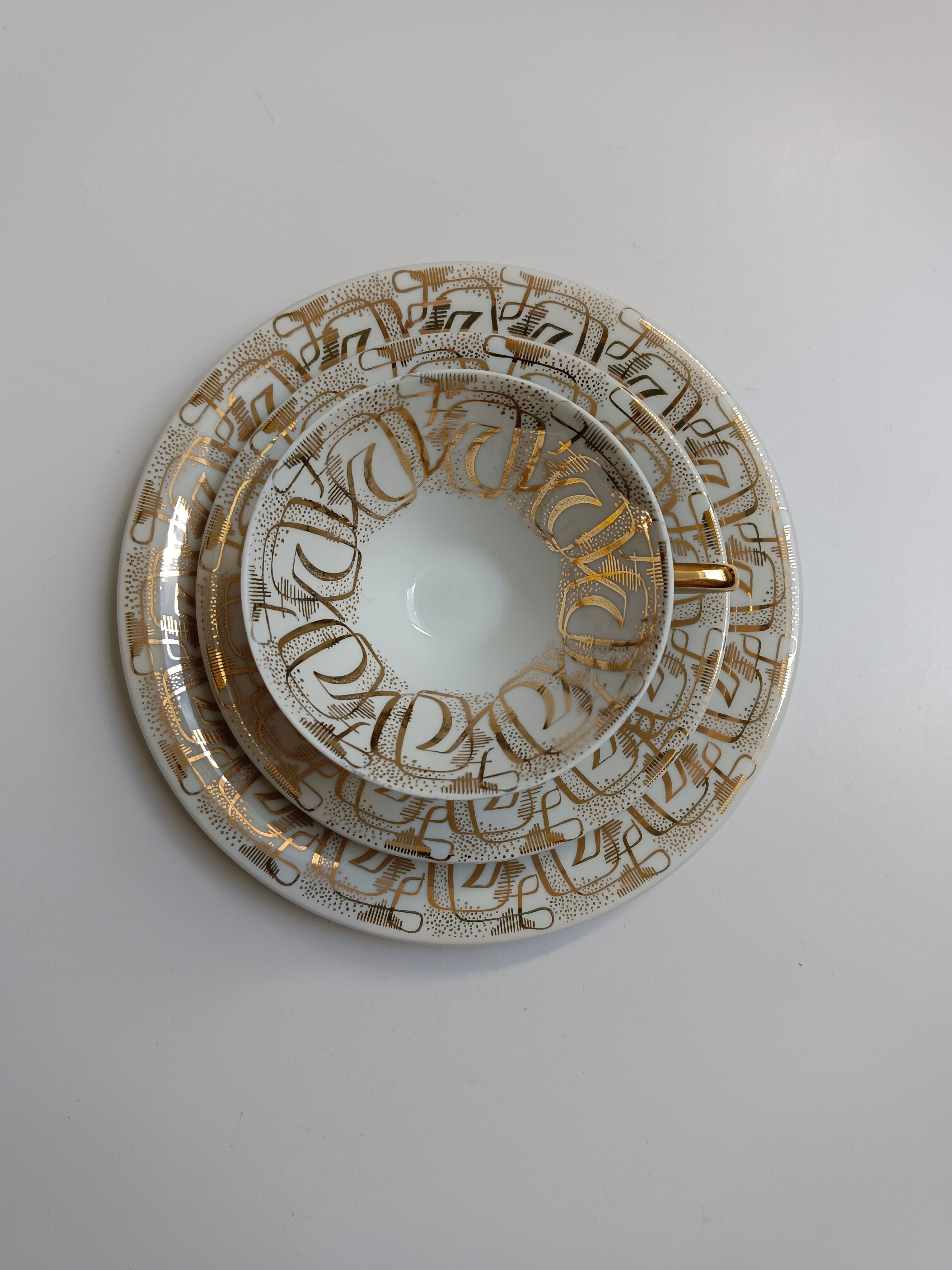 Solitaire tea cup, saucer, and dessert plate in white and gold.