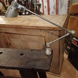 Small, very old, brutalist workbench equipped with a period workshop lamp