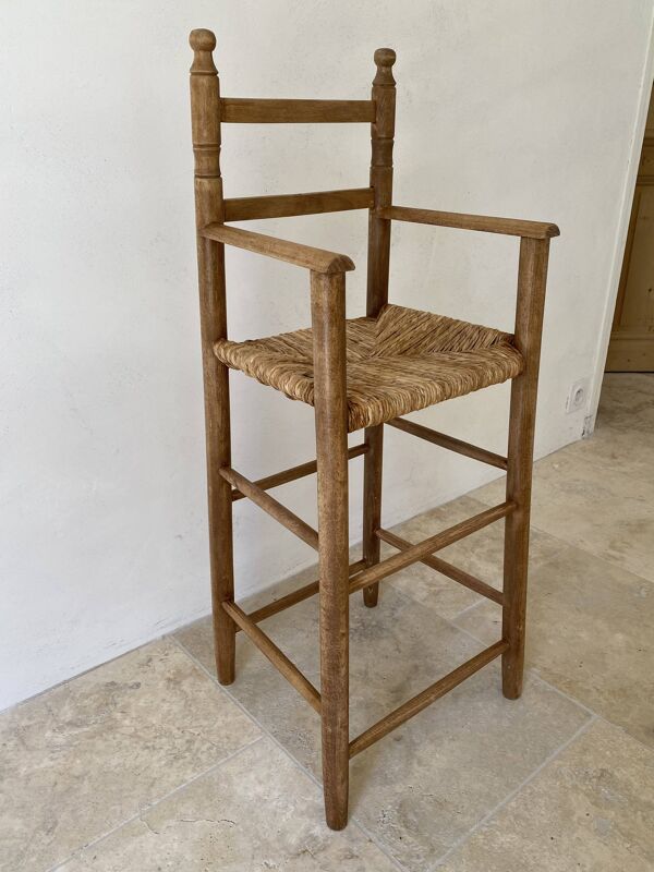 Ancienne chaise haute d’enfant en bois massif avec assise paillée.