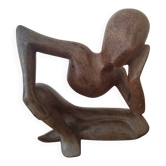 Wooden sculpted statuette of a woman in a pensive pose.