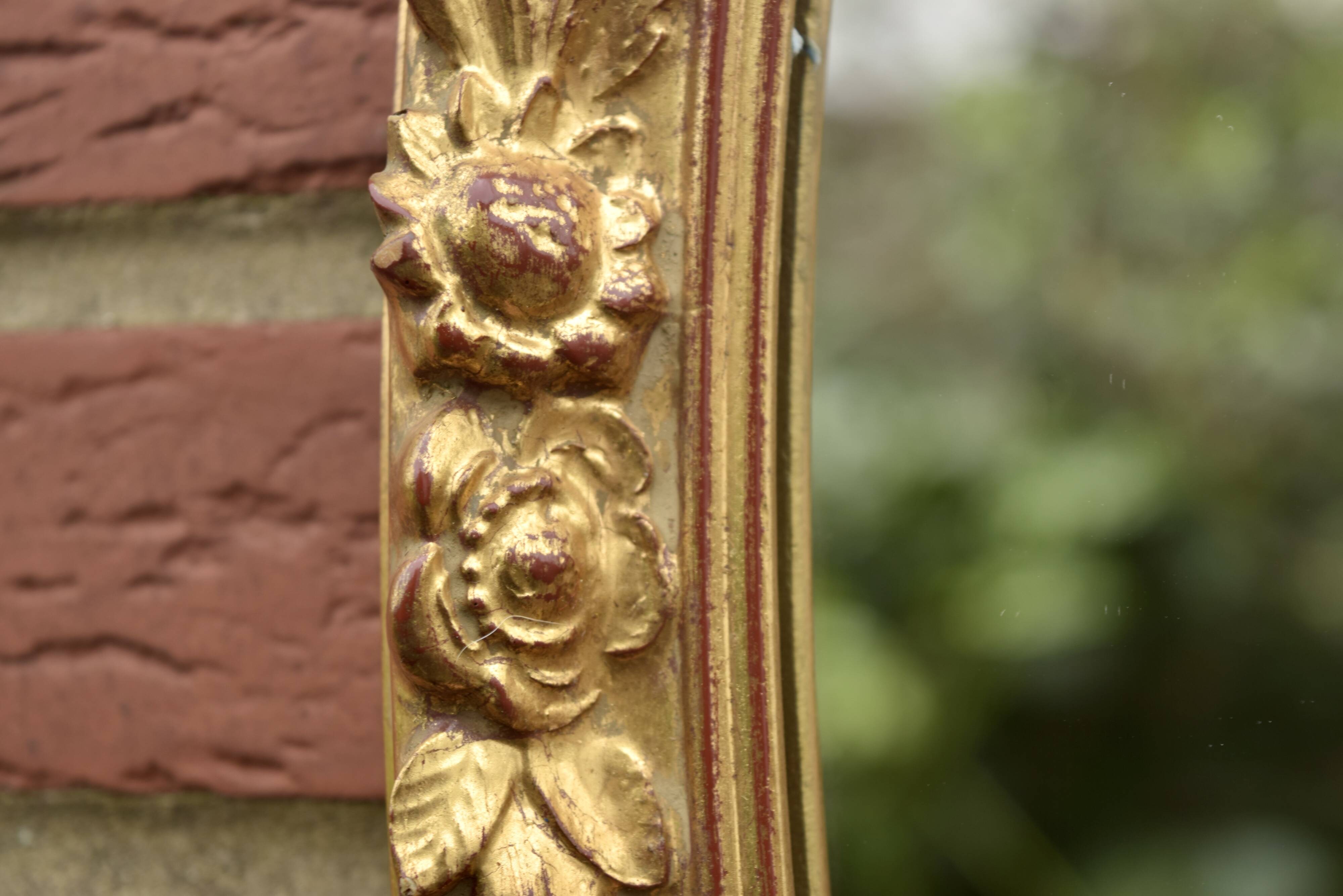 Old large oval wall mirror in golden resin