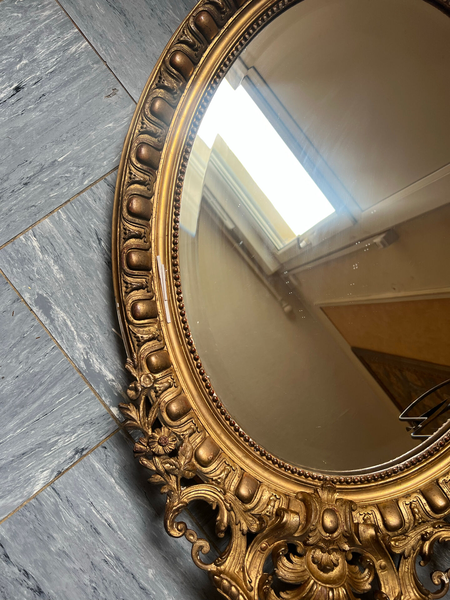 Antique oval mirror in gilded stucco with ornamentation