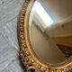 Antique oval mirror in gilded stucco with ornamentation