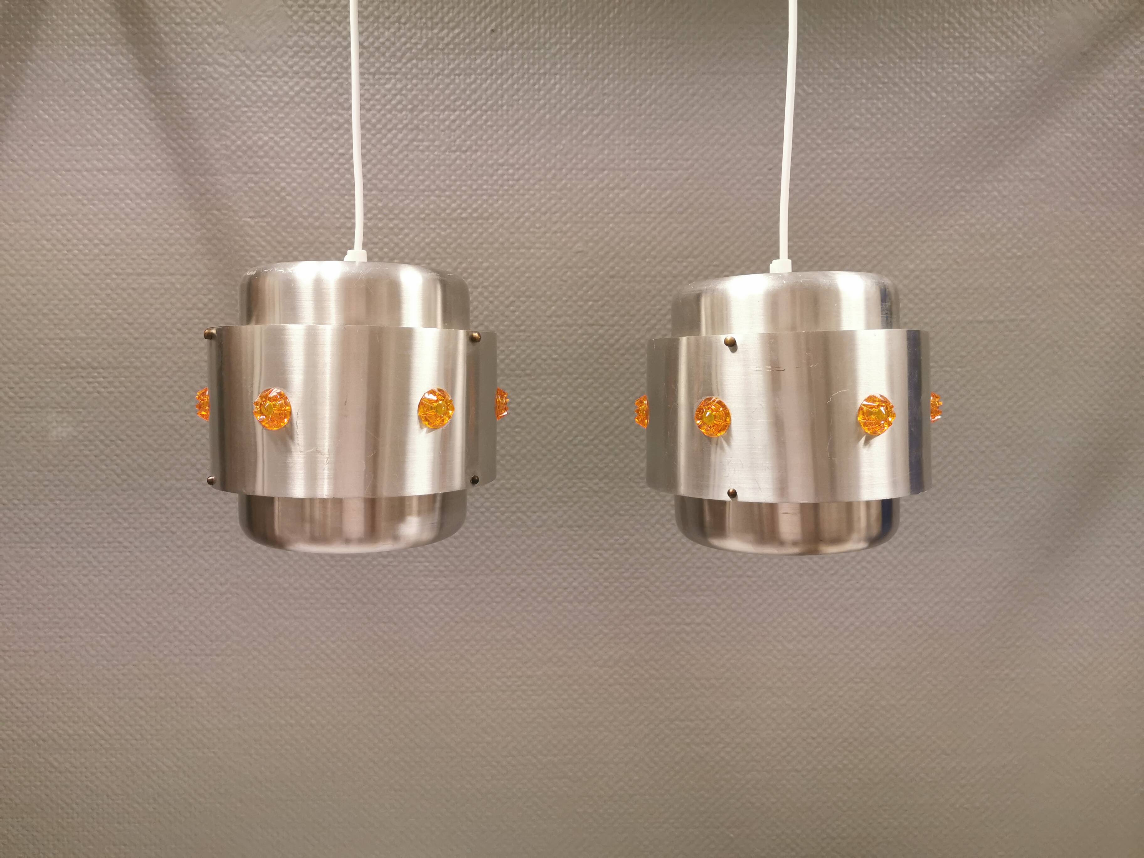 Two Space-Age hanging lamps, in silver-coloured aluminium with orange prisms.