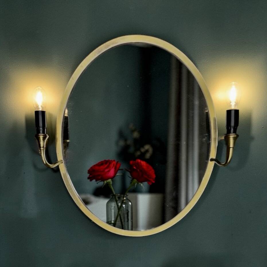 Oval wall mirror in gilded brass with double sconces – 1950s/60s