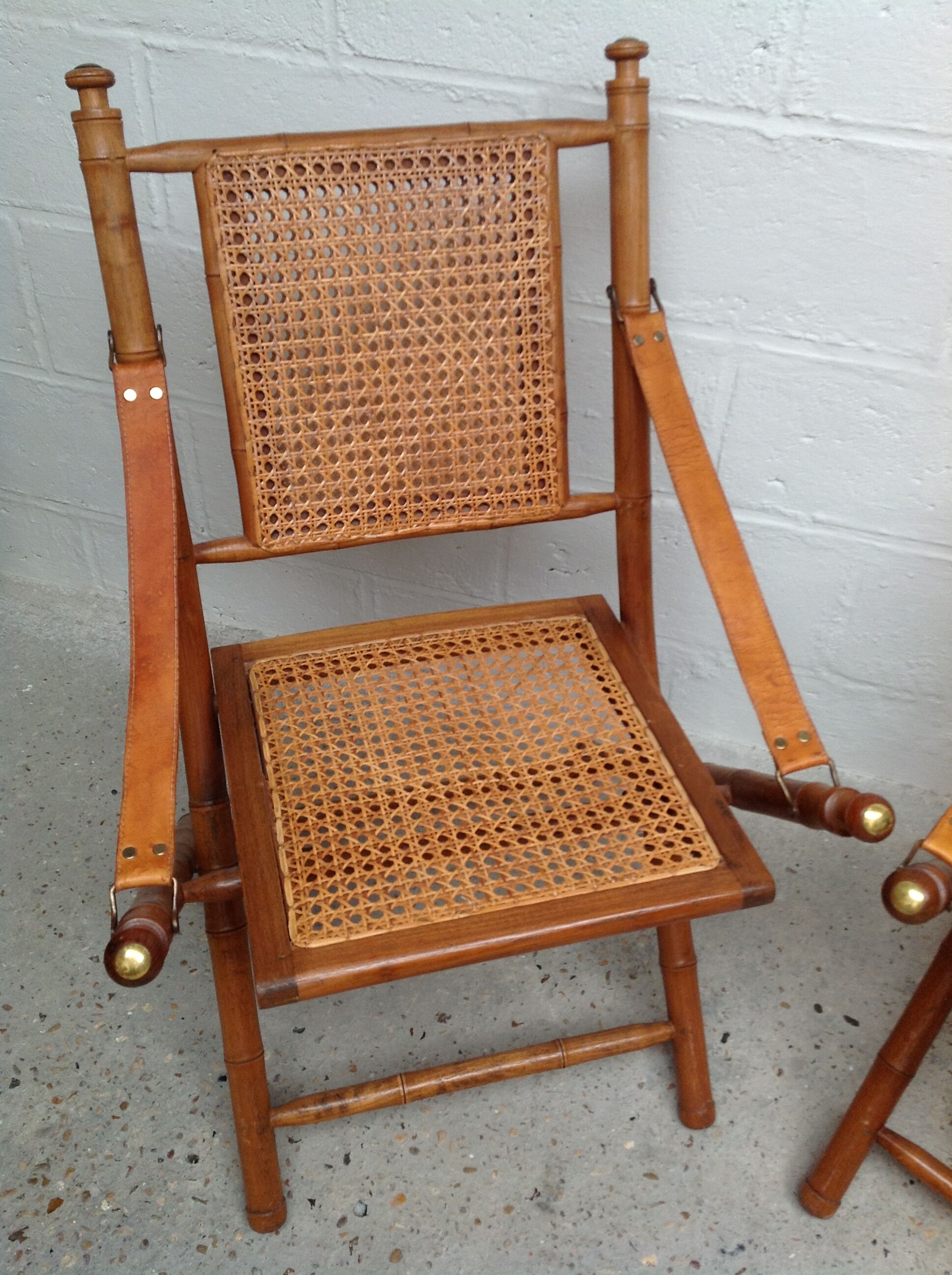 Pair of folding chairs in bamboo and caning, leather and brass