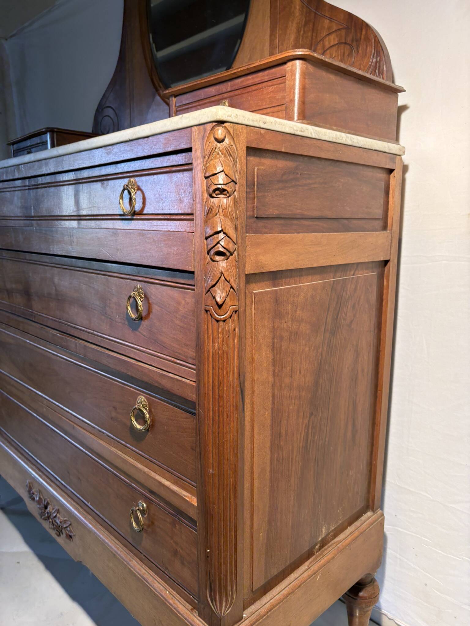 Antique carved wooden dressing table with marble and tilting oval mirror.