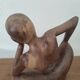 Wooden sculpted statuette of a woman in a pensive pose.