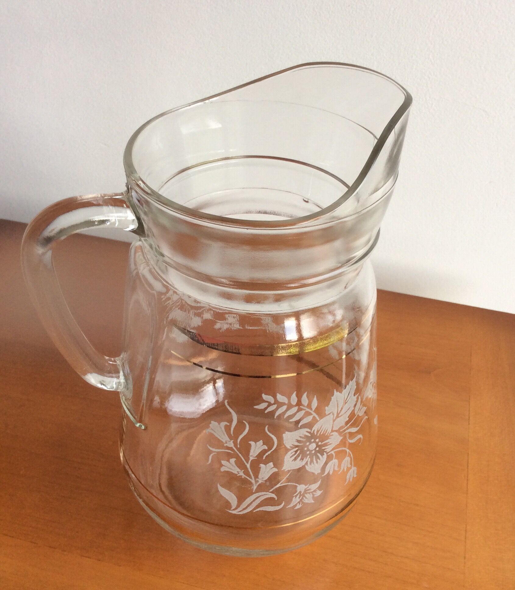 Old glass water pitcher with white flowers in relief with gold edging