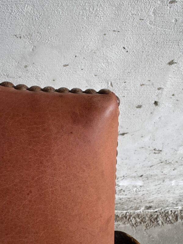 Fauteuil brutaliste en bois massif brun foncé avec assise en rotin naturel et dossier en cuir cognac