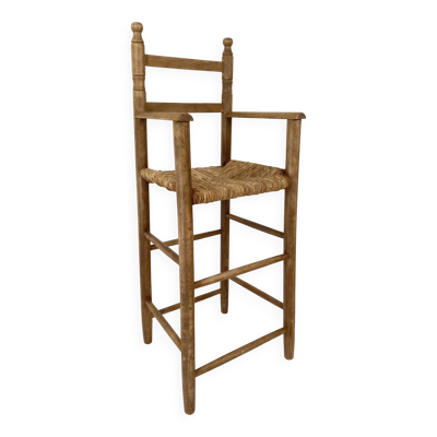 Ancienne chaise haute d’enfant en bois massif avec assise paillée.