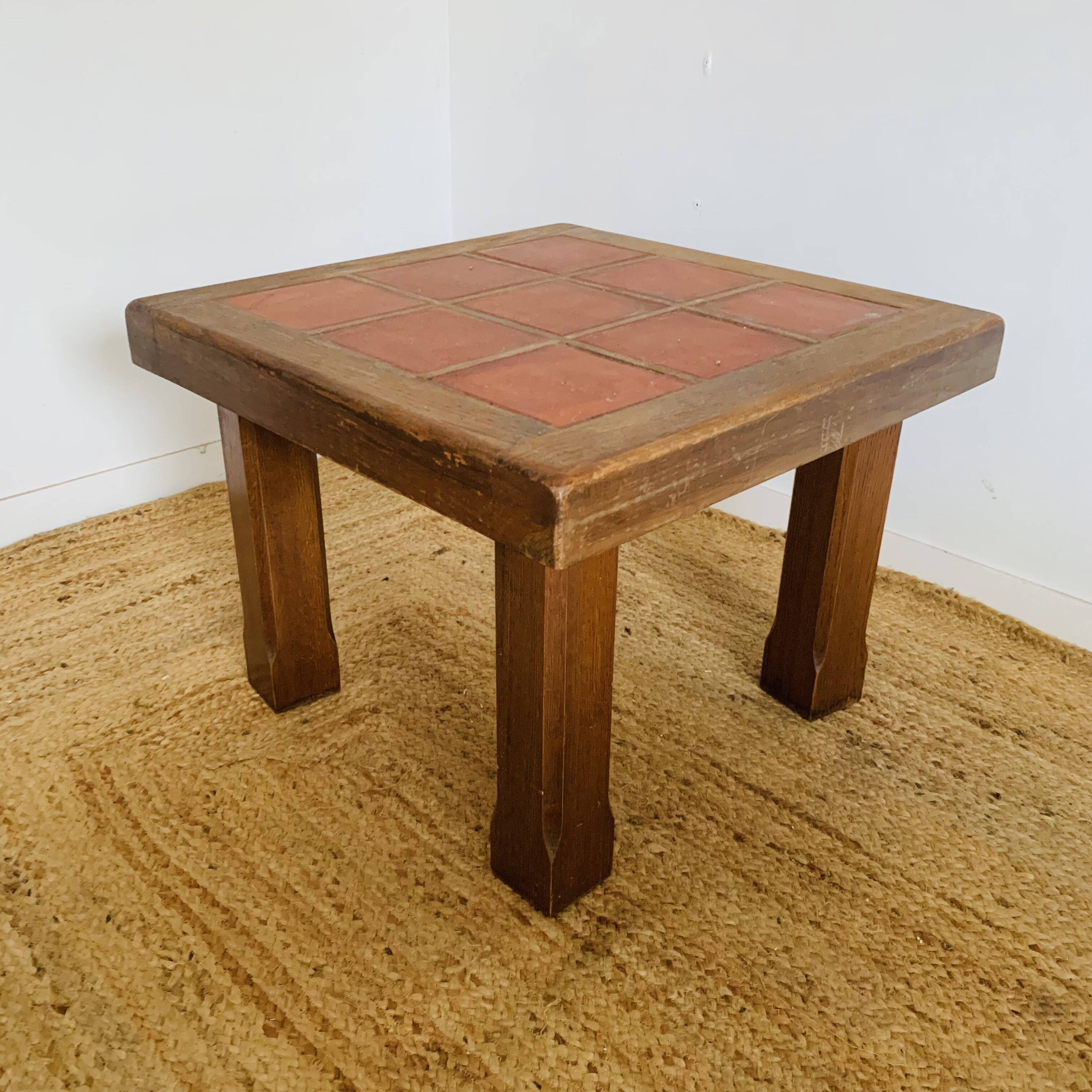 Square table with red tiles signed.