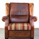 Very large worn sheepskin wing chair with a checked seat cushion