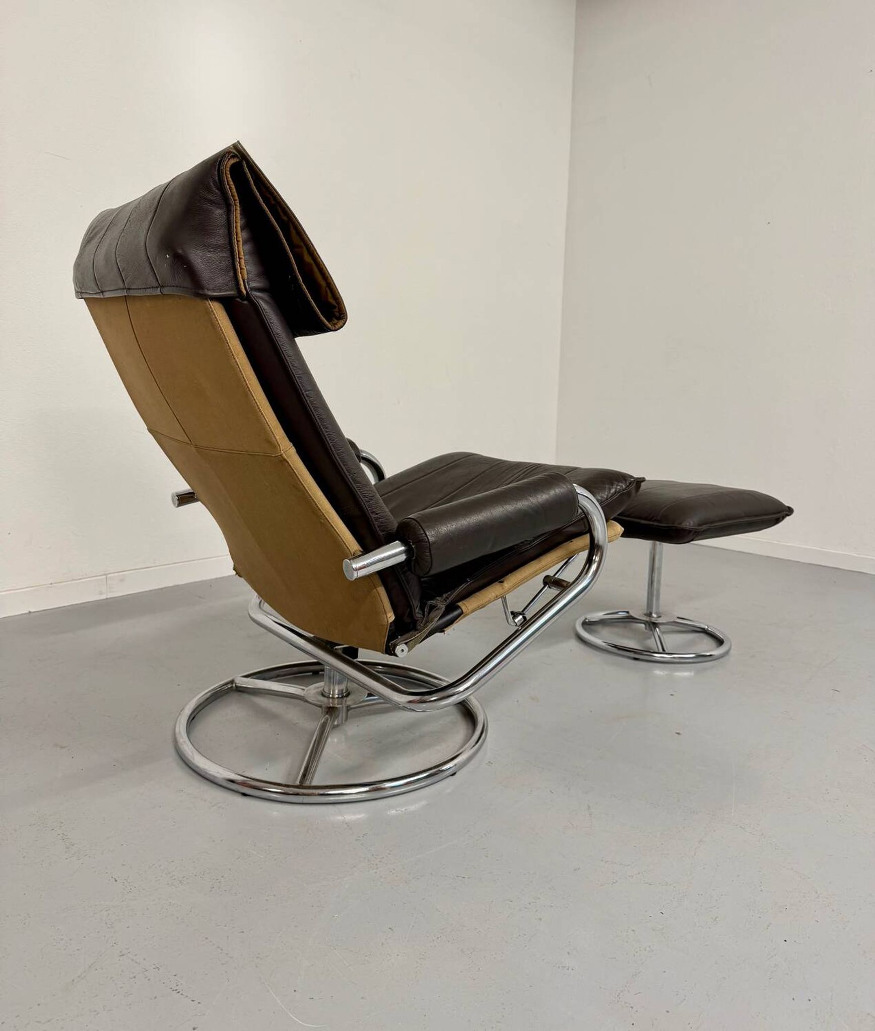 Vintage leather reclining armchair and its 1970s designer ottoman.