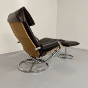 Vintage leather reclining armchair and its 1970s designer ottoman.