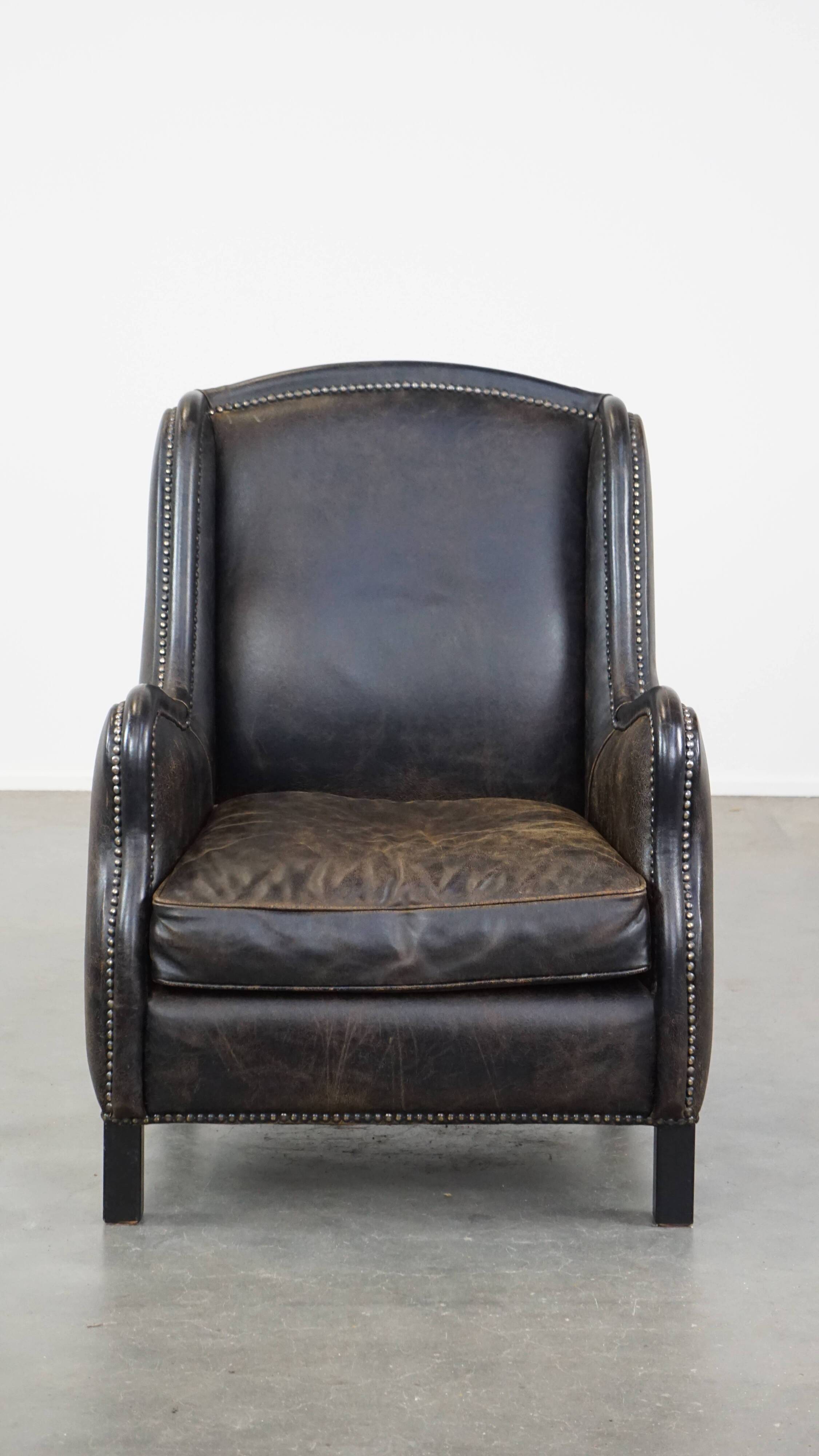 Black cow leather armchair in industrial style finished with decorative nails