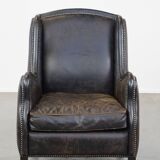 Black cow leather armchair in industrial style finished with decorative nails