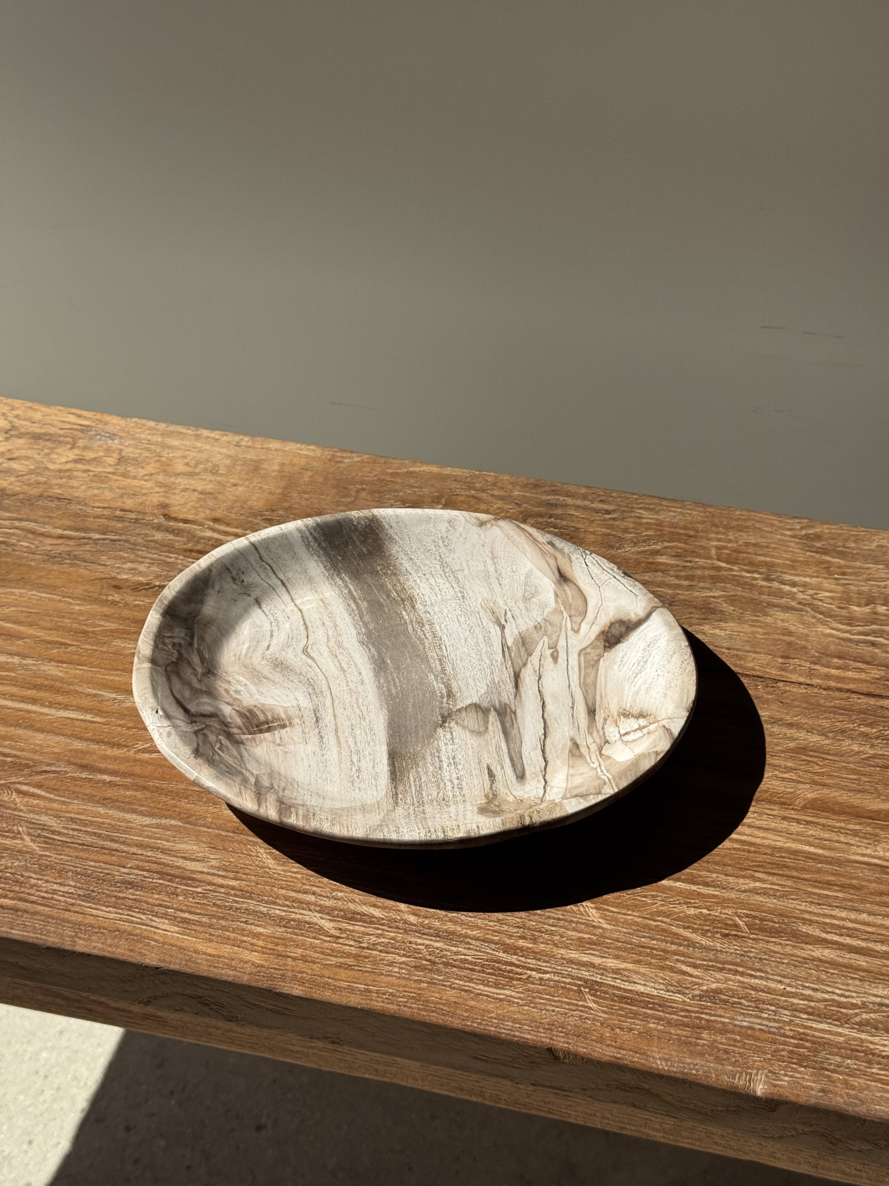 Tray, circular dish or plate made of white striped grey petrified wood.