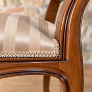 Two-seater bench in carved wood, with curved armrests.