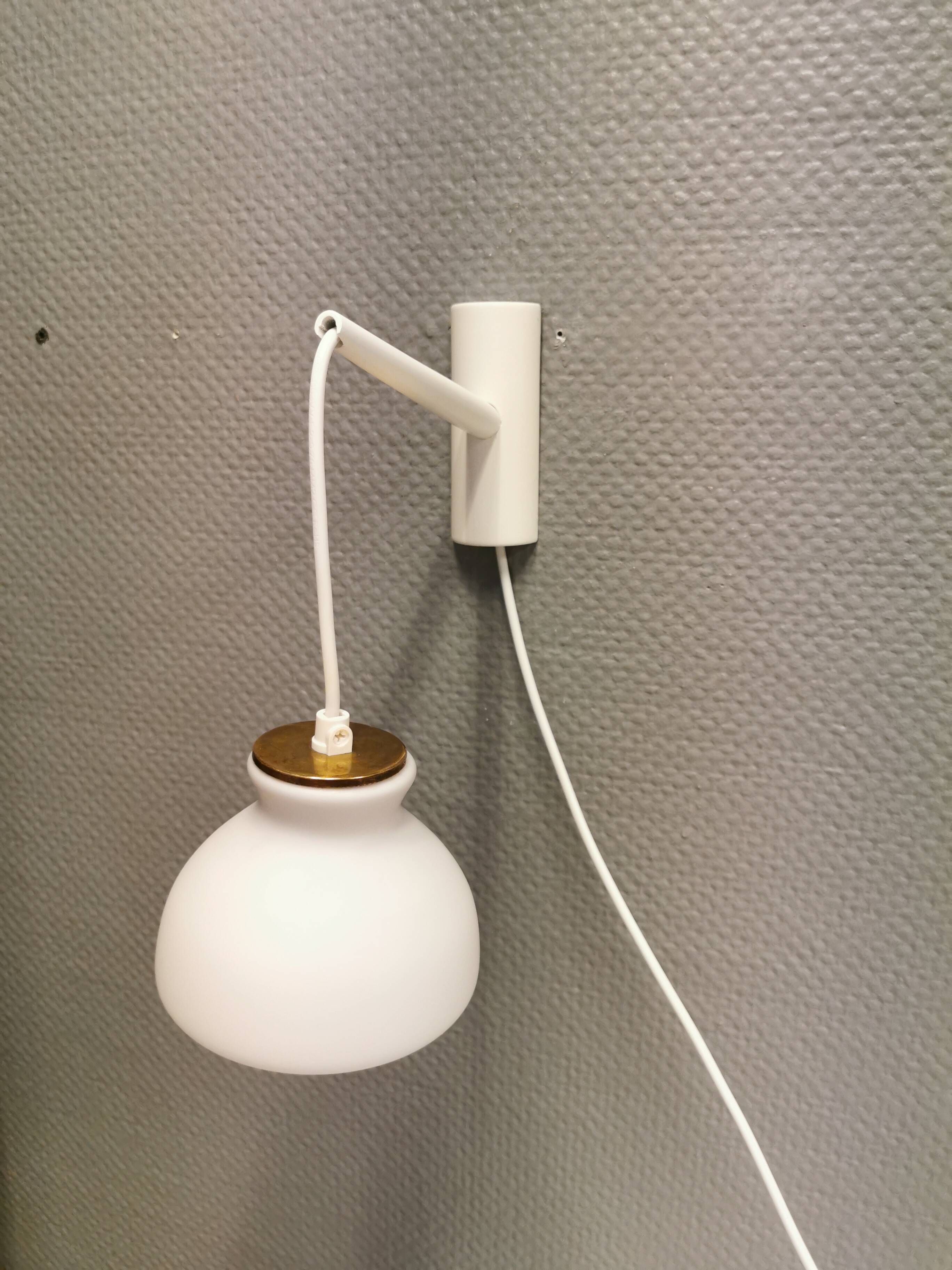 Milky white Holmegaard wall lamp with glass shade and a brass detail on top. Wooden wall bracket