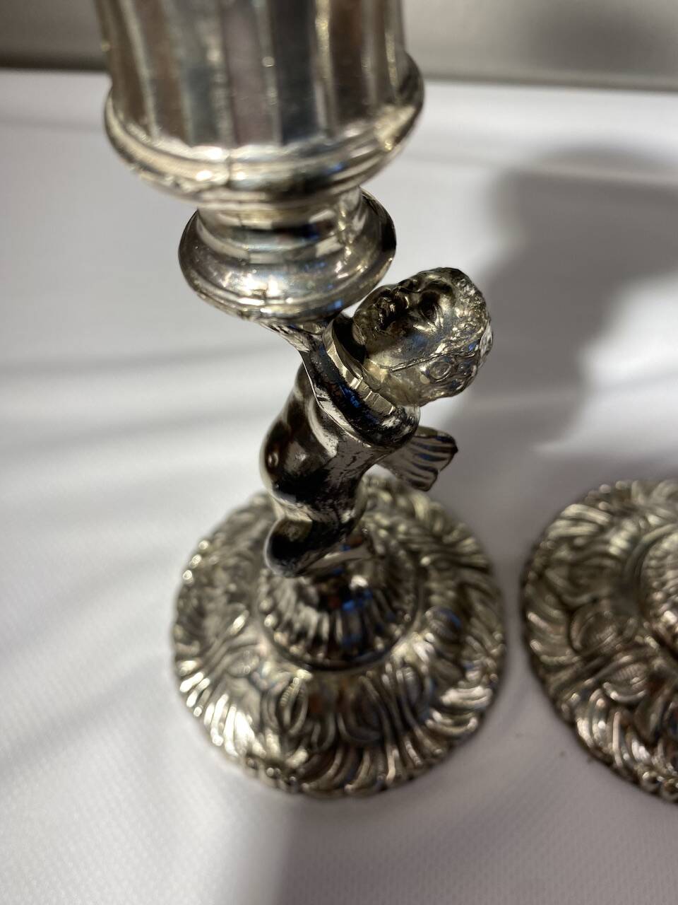 Two silver-plated metal candlesticks decorated with cherubs, 20th century