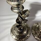 Two silver-plated metal candlesticks decorated with cherubs, 20th century