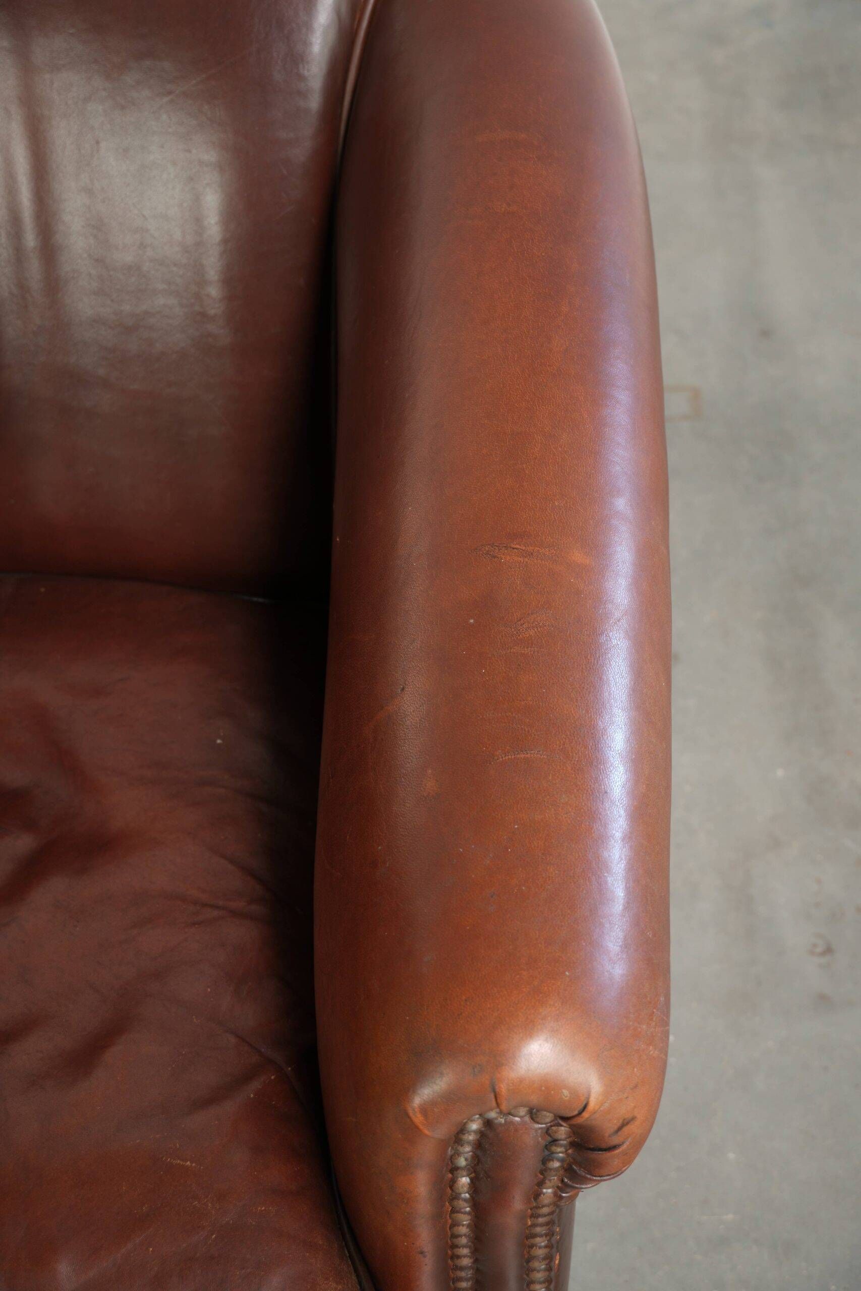 Characterful sheepskin club armchair in a dark cognac colour in English style