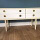 White retro wooden commode in Mid-Century style, tapered legs and gold handles (1960s)