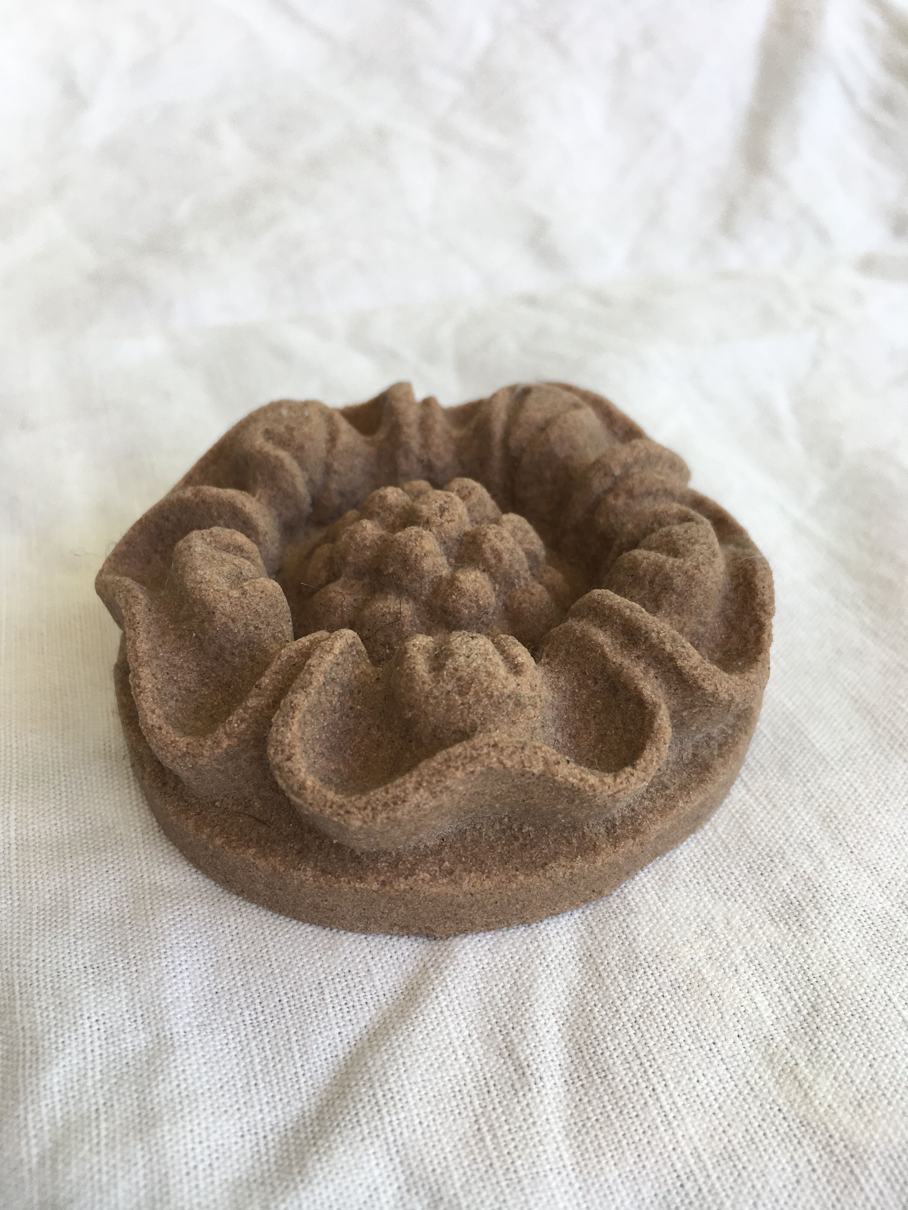 Pink sandstone paperweight in the shape of a rosette