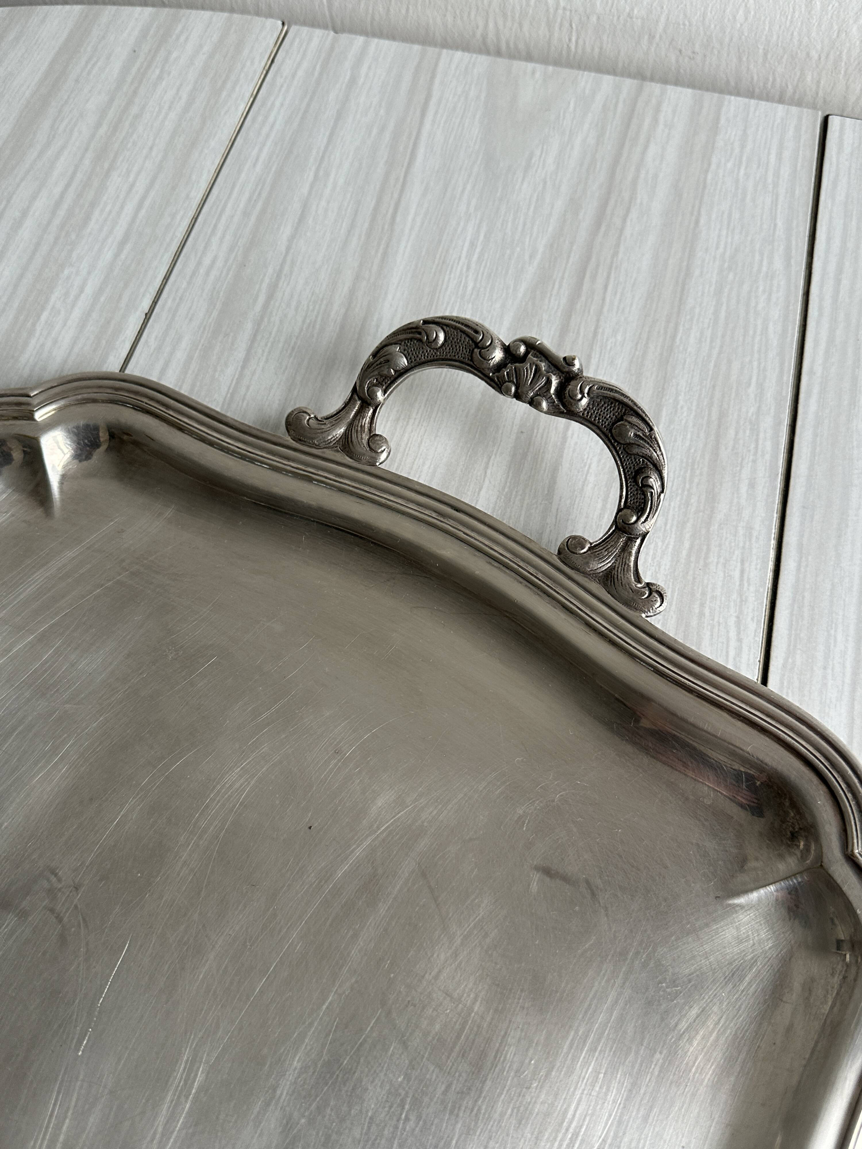 Silver metal serving tray with sculpted handles