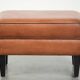 Handy sheepskin ottoman with warm colours finished with black piping