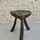 Tripod stool made of solid wood, with a carved seat.