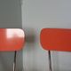 Chairs in red-orange formica and chrome metal.